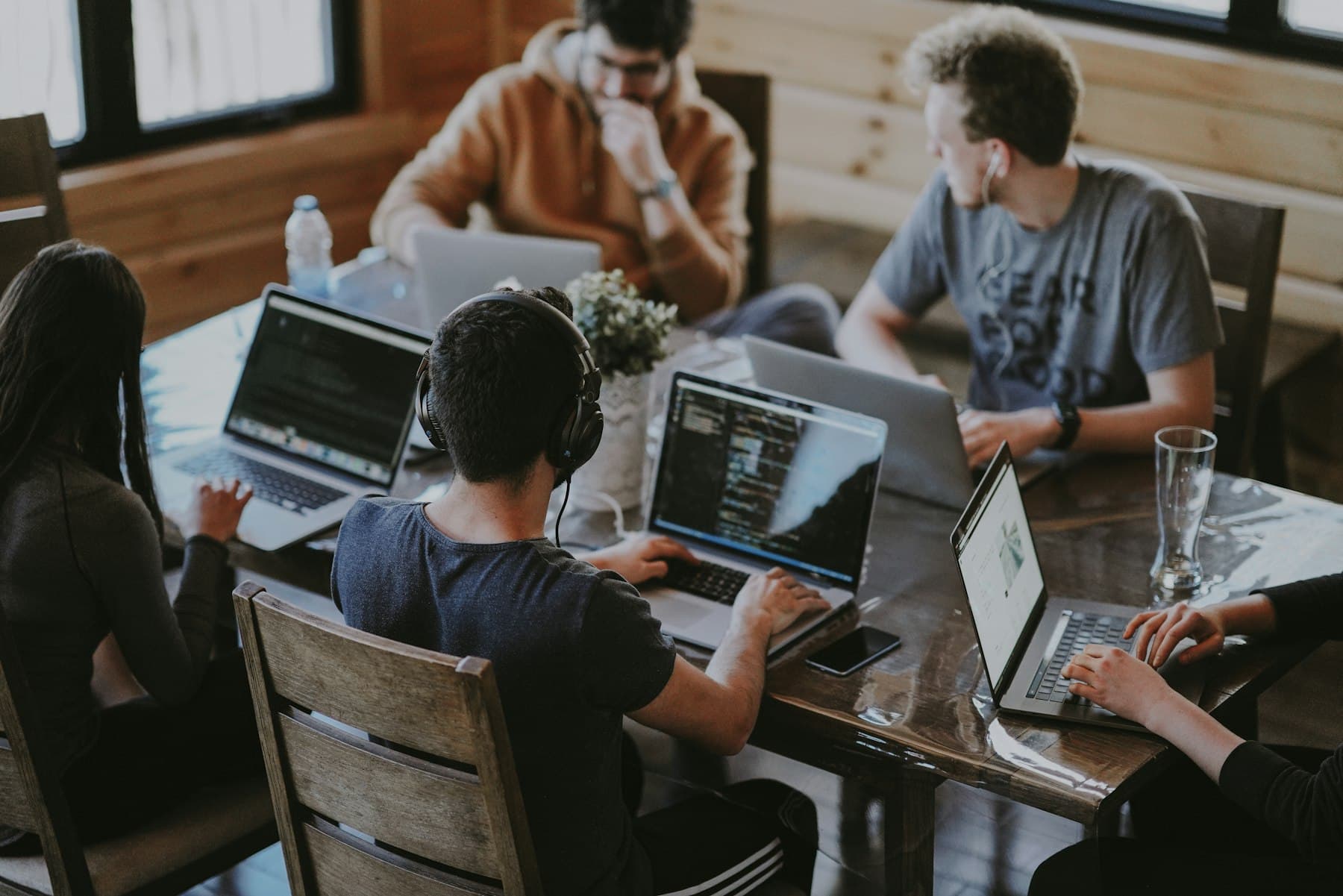 A small team working together on laptops around a wooden table
